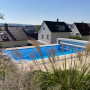 Blick über hohe Gräser über den Pool