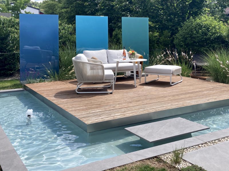 Loungeterrasse aus HOlz mit Wasserbecken und farbigen Glaselementen