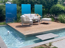 Loungeterrasse aus Holz mit Wasserbecken und farbigen Glaselementen